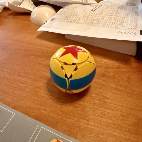 A yellow ball in the style of the Pixar ball made out of Legos.