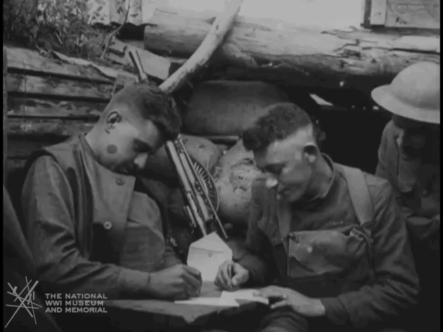 Soldiers writing letters in a trench.