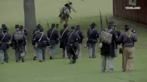 Union soldiers crossing a field firing.
