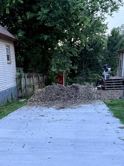Smaller pile of wood chips on a driveway.