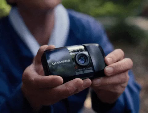 A man with a small film camera taking a picture.