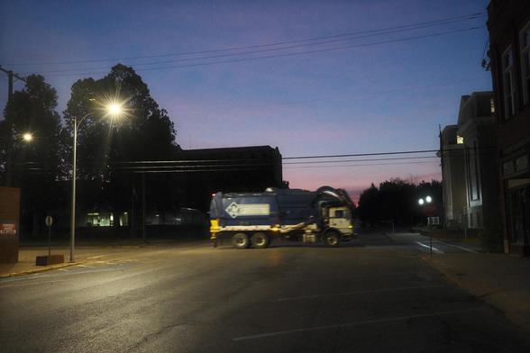A garbage truck crossing a street.