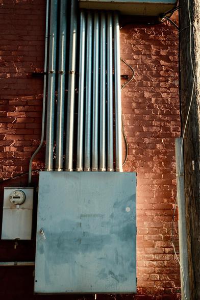 Electrical conduit and a breaker box on a brick building.