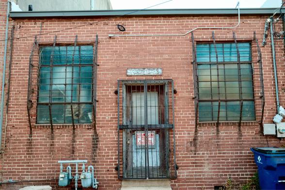 Back of a building with barred windows and doors.
