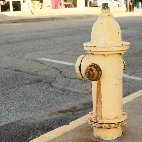 Yellow fire hydrant with rust running down one side.