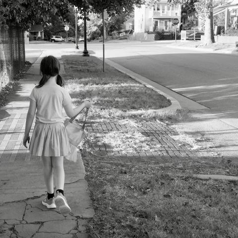 Girl with pigtails walking down sidewalk.