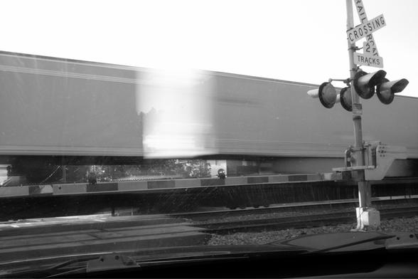 Train cars going past a railroad crossing.