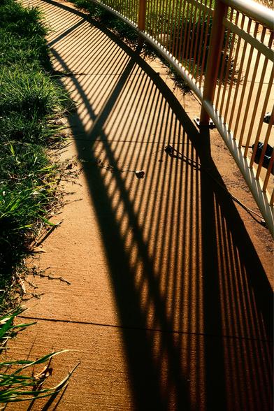 Shadow from a railing landing on a sidewalk
